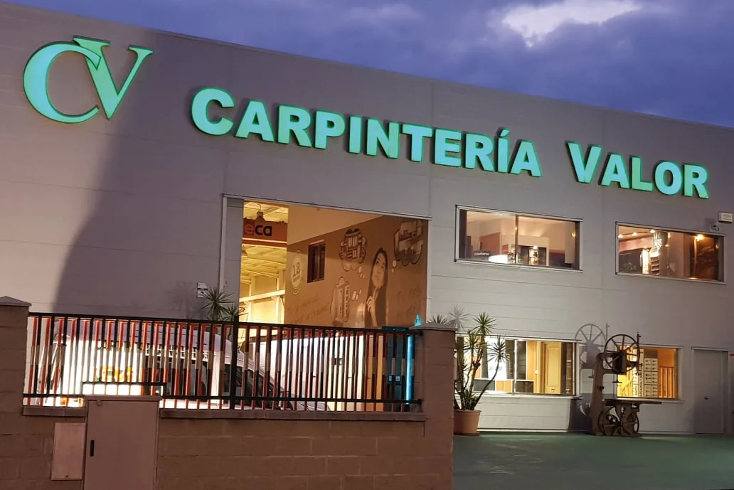 Fachada iluminada del taller de Carpintería Valor