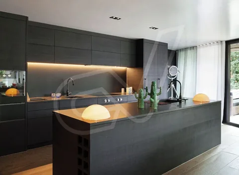 Cocina oscura con isla central y encimera de madera