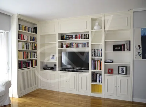 Librería en esquina con módulos altos y bajos alrededor de un televisor