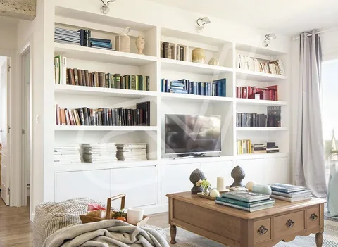 Librería blanca con cajones bajos y baldas superiores en un salón