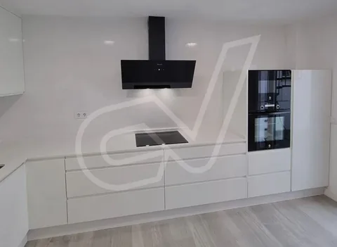 Cocina blanca con campana decorativa y placa de inducción