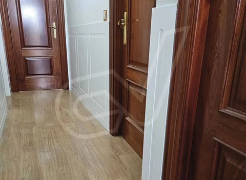 Puertas de madera oscura en un pasillo con suelo de tarima