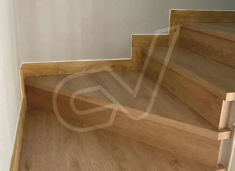 Escalera revestida de madera con peldaños y zanquines a medida